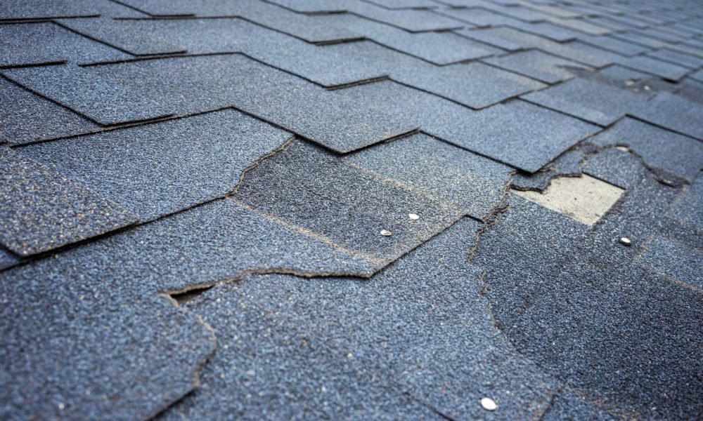 Сlose up view of bitumen shingles roof damage that needs repair.